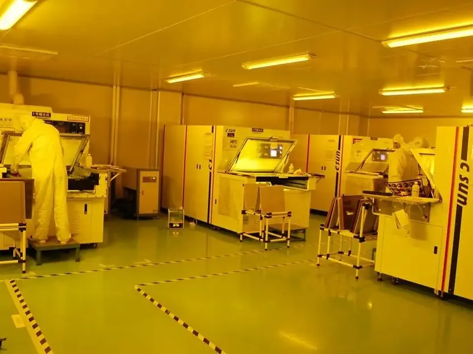 Operators running photolithography equipment under yellow cleanroom light